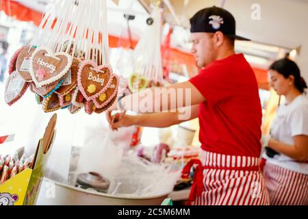 Heidelberg, Germania. 03 luglio 2020. Josef Lala si trova di fronte a un contenitore con caramelle di cotone accanto a cuori di pan di zenzero appesi in un carro di showman che offre caramelle di cotone e mandorle tostate. La città di Heidelberg sta creando nuove opportunità per alcuni showmen, che sono stati gravemente colpiti dalla crisi di Corona, di guadagnare denaro. Una dozzina di proprietari di stalle hanno venduto dolci e vari piatti nel centro della città dalle 11 alle 20 dal venerdì. Credit: Uwe Anspach/dpa/Alamy Live News Foto Stock