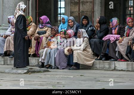 Un gruppo di donne musulmane che indossano i foulard siedono su un gradino all'interno del cortile della Moschea Blu nel distretto di Sultanahmet di Istanbul, in Turchia. Foto Stock