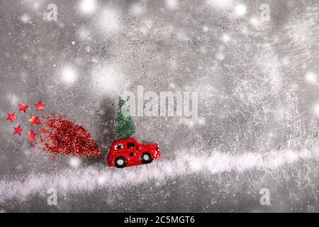 Giocattolo di Natale rosso auto con abete sul tetto su strada neve con rosso sequin fumo. Foto Stock