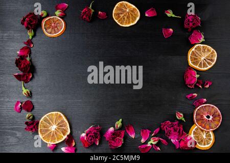 Fondo in legno con rose secche e petali e fette di arancio secco con spazio per la copia. Composizione piana con bordo di cornice in rose secche e cit Foto Stock