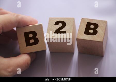 Abbreviazione B2B in lettere su cubi di legno. La mano di concetto di affari o di busness ha messo un cubo B alla fila. Concetto di strategia di marketing aziendale Foto Stock