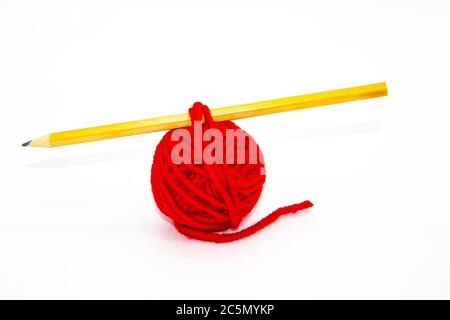 Matita rossa sul filo con la matita su sfondo bianco. Sfera rossa di filo rosso di lana isolato su bianco Foto Stock