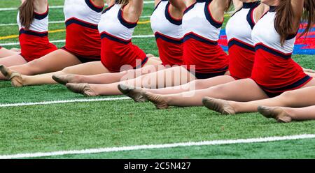 La squadra di Kickling termina la sua performance in full front split su campo di erba verde. Foto Stock