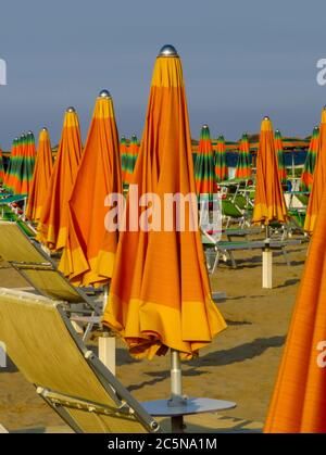 Ombrelloni arancioni chiusi sulla spiaggia di Rimini in Italia Foto Stock