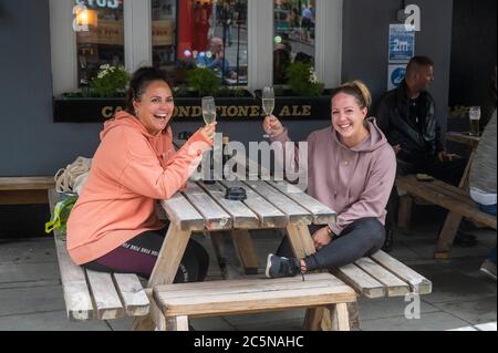 Brighton UK 4 luglio 2020 - giovani donne godersi un drink al Wagon & Horses a Brighton come pub riaprire su quello che è stato chiamato Super Sabato in Inghilterra . Pub, hotel parrucchieri e ristoranti sono tra le imprese che sono autorizzati ad aprire di nuovo le loro porte, come le restrizioni di blocco sono più attenuati in Inghilterra durante il coronavirus COVID-19 pandemia crisi: Credit Simon Dack / Alamy Live News Foto Stock