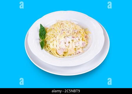 Deliziosi spaghetti italiani Carbonara con formaggio, pancetta e menta fresca isolati su sfondo blu Foto Stock