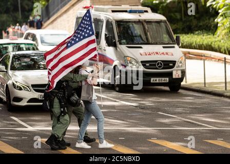 Hong Kong, Cina. 4 luglio 2020. Una donna è scortata dalla polizia mentre mostra una bandiera degli Stati Uniti per celebrare il 04 luglio Independence Day al di fuori del Consolato Generale degli Stati Uniti a Hong Kong, Cina, il 04 luglio 2020. Il 02 luglio il Senato degli Stati Uniti ha approvato definitivamente l'Hong Kong Autonomy Act, che richiede sanzioni obbligatorie contro individui e banche stranieri per l'erosione dell'autonomia di Hong Kong. Credit: May James/ZUMA Wire/Alamy Live News Foto Stock