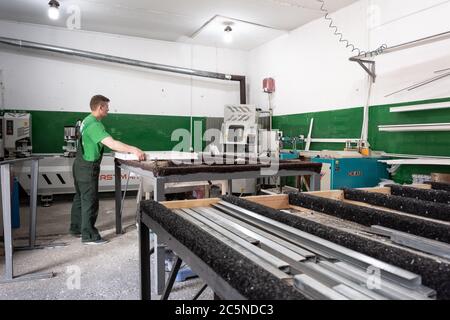 Operatore su una macchina per la saldatura di finestre e porte in PVC. Fabbrica per la produzione di serramenti e porte in alluminio e PVC. Foto Stock