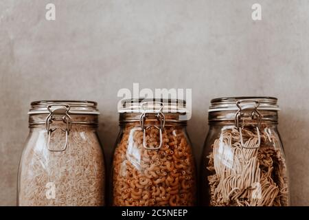 Tre contenitori in vetro pieni di ingredienti alimentari secchi non cotti.  Riso, pasta, farina, zucchero Foto stock - Alamy