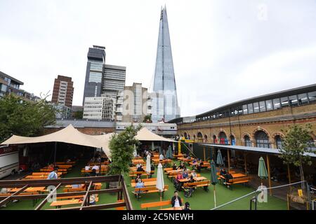 La gente gusteranno bevande al bar Acetar Yard, Londra, riaprirsi dopo l'allentamento delle restrizioni di blocco del coronavirus in tutta l'Inghilterra. Foto Stock