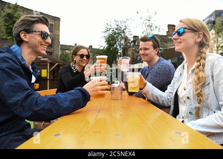 La gente gusteranno bevande al bar Acetar Yard, Londra, riaprirsi dopo l'allentamento delle restrizioni di blocco del coronavirus in tutta l'Inghilterra. Foto Stock