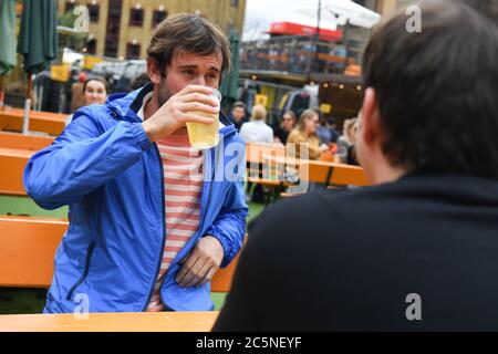 La gente gusteranno bevande al bar Acetar Yard, Londra, riaprirsi dopo l'allentamento delle restrizioni di blocco del coronavirus in tutta l'Inghilterra. Foto Stock