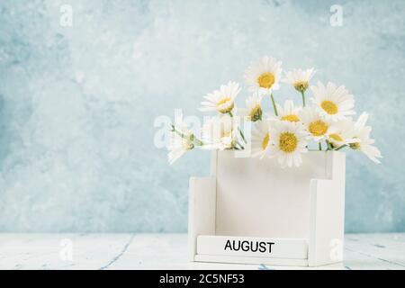 Calendario cubo bianco per agosto decorato con fiori margherita su blu con spazio copia Foto Stock