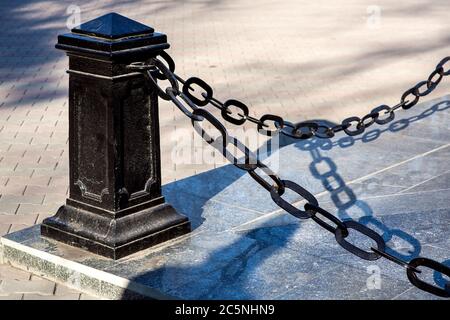 barriera protettiva di ferro nero con una catena che racchiude l'apostamento marmoreo del monumento. Foto Stock