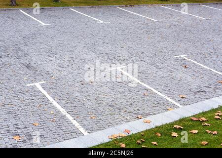 Parcheggio vuoto per auto pavimentate con piastrelle di pietra grigio quadrate con strisce bianche marcate Vista dall'alto parco, intorno ai prati del parcheggio con erba cosparsa di YE Foto Stock