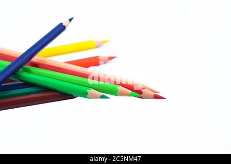 Primo piano di una pila di diversi pastello a matita di legno su uno sfondo di carta bianca Foto Stock