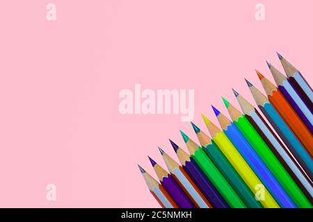 Fila di diversi colori pastello a matita di legno su una singola carta di colore rosa Foto Stock
