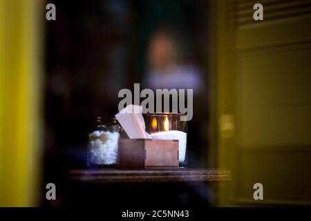 Tavolo da ristorante attraverso il bicchiere dalla strada, una serata romantica con candele in un bicchiere sul tavolo. Foto Stock