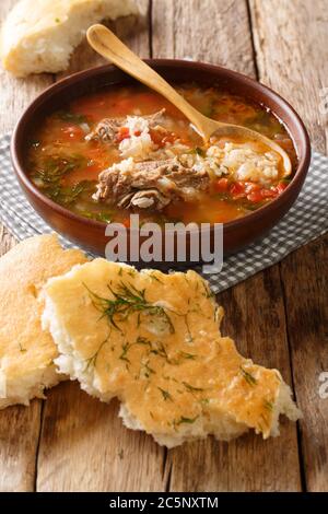 Gustosa zuppa tradizionale di manzo e riso con spezie e verdure servite con pane pita da vicino sul tavolo. Verticale Foto Stock