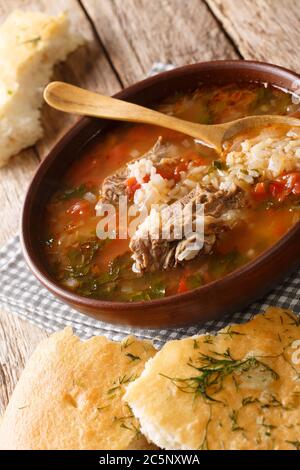 Zuppa georgiana di Kharcho in una ciotola servita con il pane di chiodo di garofano sul tavolo. Verticale Foto Stock