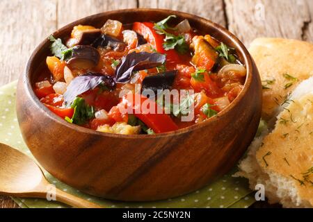 Antipasto estivo speziato di melanzane, cipolle, pomodori e peperoni dolci da vicino in una ciotola sul tavolo. Orizzontale Foto Stock