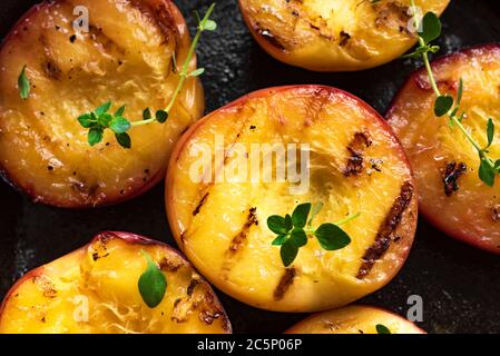 Pesche grigliate con Thyme, Miele primo piano. pesche arrosto o nettarine al barbecue fatte in casa, dessert rustico estivo o autunnale. Foto Stock