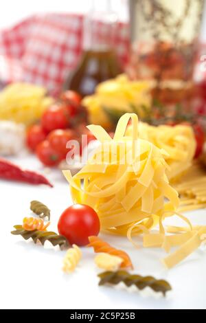 Gustosi e appetitosi classici spaghetti italiani con pomodoro e pasta in prima linea. Olio d'oliva, funghi e verdure sullo sfondo. Foto Stock