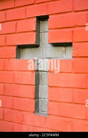 Parete fatta di mattoni rossi. Croce cristiana tra mattoni - simbolo del cristianesimo Foto Stock