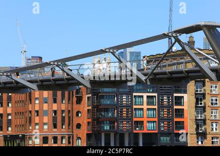 Il Millennium Bridge sul Tamigi con moderni uffici e appartamenti lungo il fiume, oltre, Regno Unito Foto Stock