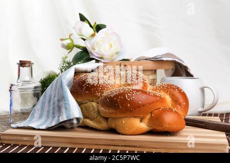 un filone intrecciato di pane all'uovo di sesamo su un legno tagliere con coltello isolato su bianco Foto Stock