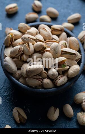 Pistacchi arrosto e salati in ciotola di ceramica Foto Stock