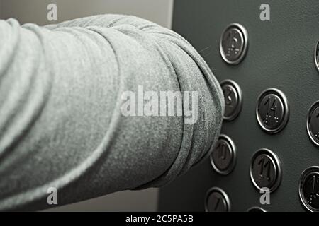 Premendo i pulsanti nell'ascensore con guanti, gomito. Quarantena e sicurezza pandemica. Foto Stock