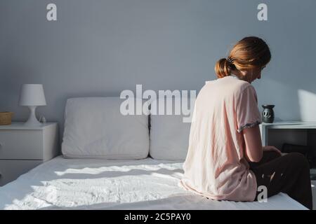 Donna infelice o sonnolenta siede sul lato di un letto vuoto. Concetto di depressione, disturbi del sonno o malattia Foto Stock