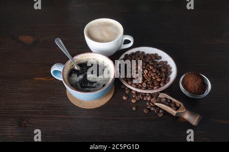 Tazze di caffè, chicchi di caffè tostati e polvere macinata su sfondo tavola di legno da cucina. Foto Stock