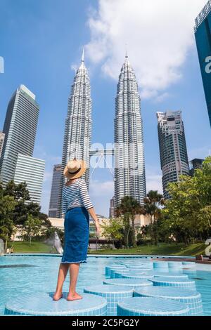 Kuala Lumpur City, Malesia – 12 MARZO 2019: Giovane turista femminile in cappello di paglia godendo di due grattacieli Petronas Towers nel centro di Kuala Lumpur Foto Stock