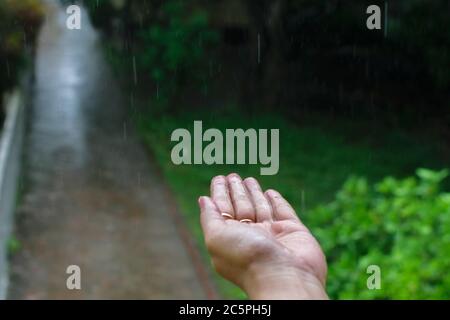 Mano umana bagnata isolata con gocce di pioggia che cadono su di essa Foto Stock