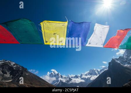 Il Sacro buddista che prega bandiere multicolore con mantra che battono e ondeggiano sul vento forte con vista della valle e Ama Dablam 6812m peak.Everest base Foto Stock