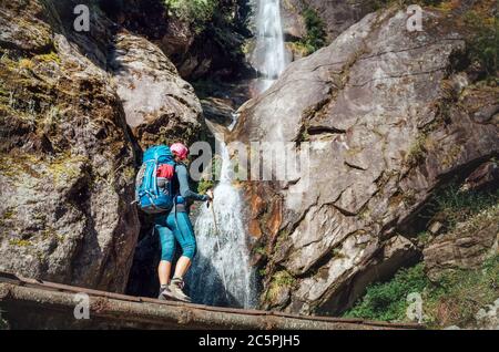 Giovane escursionista zaino in spalla donna utilizzando pali da trekking godendo la piccola cascata vista sulla Everest base Camp percorso trekking durante l'alta altitudine Acclimat Foto Stock
