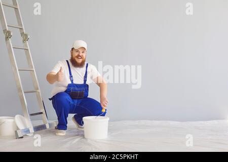 Pittura di pittore. Divertente pittore maschile con un pattinatore a rulli in piedi dipinge sullo sfondo. Foto Stock