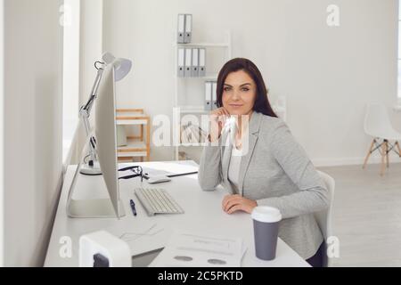 Operatore del call center donna in cuffia seduto su un computer sul posto di lavoro. Help desk concettuale in linea Foto Stock