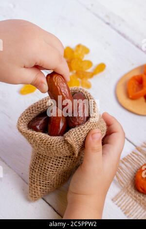 La mano mette le datteri in borsa, sackcloth e frutta secca. Concetto di eco e zero rifiuti Foto Stock