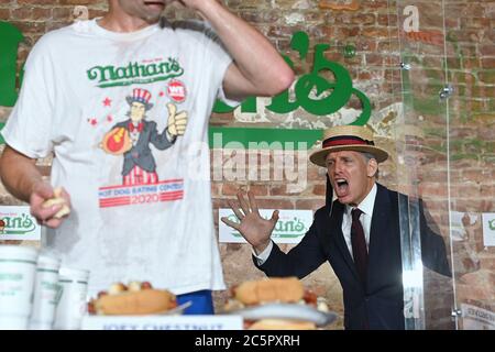 Host George Shea (cappello di paglia) Annuncia il numero di hot dog mangiati dal mangiatore competitivo Joey Chestnut mentre stabilisce un nuovo record mondiale con 75 hot dog per vincere la divisione maschile del famoso Concorso annuale Nathan's del 4 luglio International Hot Dog-eating Contest nel quartiere Brooklyn di New York City, NY, 4 luglio 2020. La competizione di quest'anno si è svolta all'interno di un edificio senza il pubblico, dove i concorrenti sono stati separati da divisori in plexiglass a causa di preoccupazioni COVID-19, e nel tempo dato di dieci minuti, Chestnut ha consumato 75 hot dog, e Sodo ha consumato 48 hot dog e mezzo. (Antonio be Foto Stock