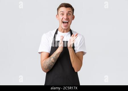 Dipendenti, negozi di alimentari e caffetteria. Il barista felice impressionato ed eccitato in grembiule nero ha clap le mani per la classe principale sulla preparazione del caffè Foto Stock