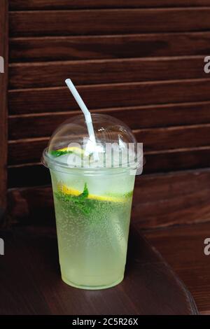 Cocktail in una tazza di plastica su sfondo di legno. Prenda Mojito takeaway, consegna di cibo. Foto Stock