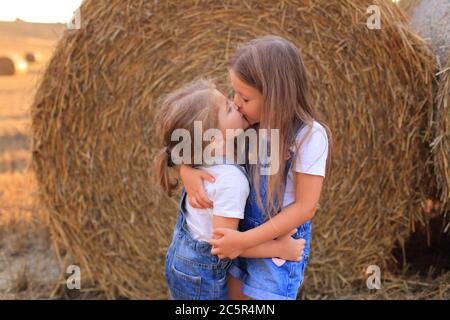 Girlfriends coccolarsi vicino ad un haystack in un campo in estate Foto Stock