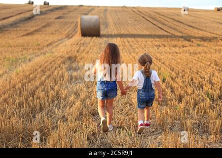 I girlfriends corrono su un campo in pendenza in estate Foto Stock