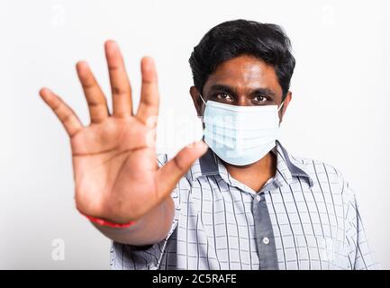 Closeup Asian bel uomo nero indossando chirurgico igienico maschera di protezione contro il coronavirus e sollevare il segno di arresto mano, studio colpo isolo Foto Stock