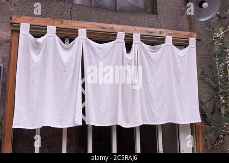 Il tessuto simile a una tenda che pende di fronte ai ristoranti e negozi tradizionali giapponesi serve non solo come un cartello, ma ha un significato più grande, Foto Stock