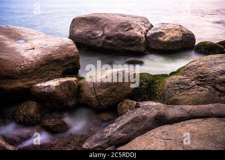 Spiaggia violenta accanto al faro sulla riva del mare arabo in India. Spiaggia rocciosa piena di barriere coralline e granchi. Foto Stock