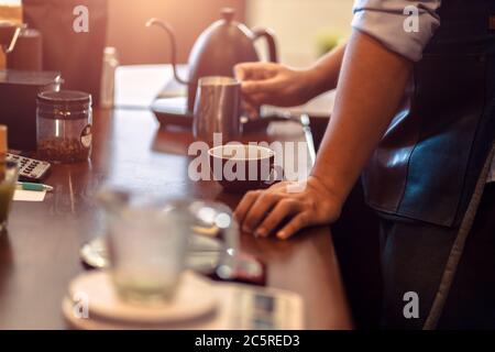 barista che prepara il cappuccino. Versare il latte per preparare una tazza di caffè. Latte art Foto Stock